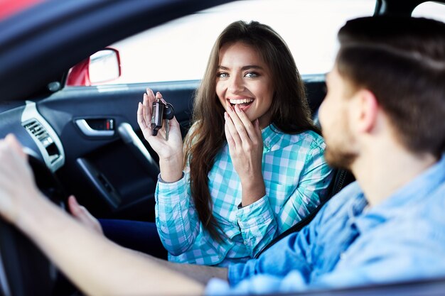 happy couple sitting new automobile looking camera smiling holding new keys exited_355000 1658